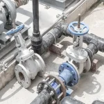 صمامات البوابة الصناعية المثبتة في نظام الأنابيب تظهر الوصلات ذات الحواف، وعجلات اليد، وتخطيط خط الأنابيب للتحكم في السوائل.